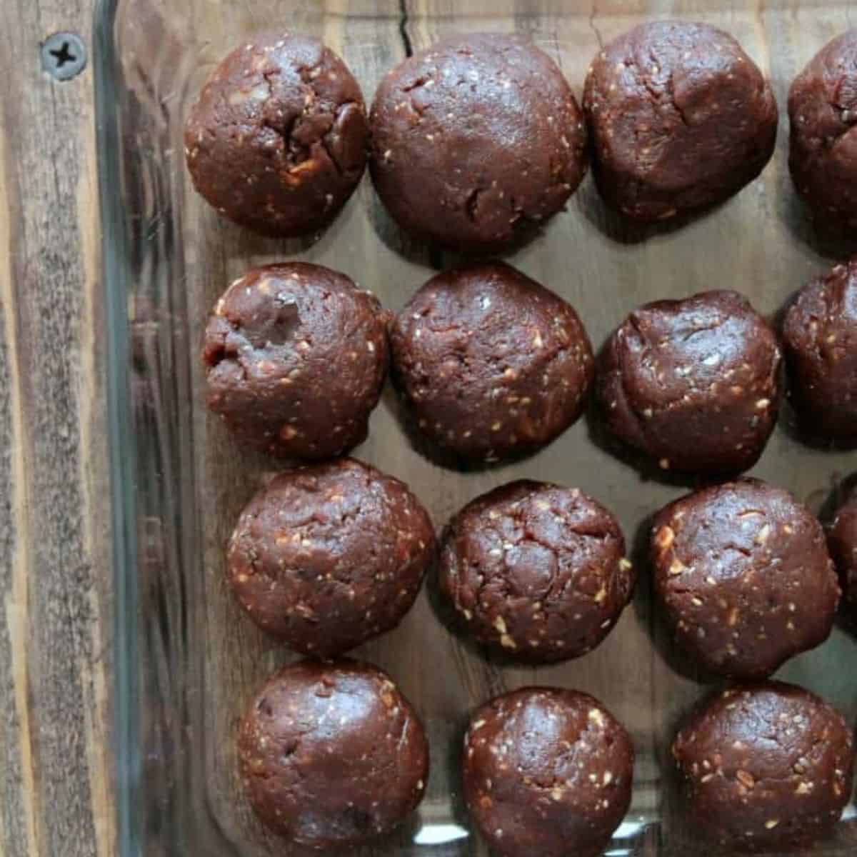 chocolate protein balls rolled in a glass container.