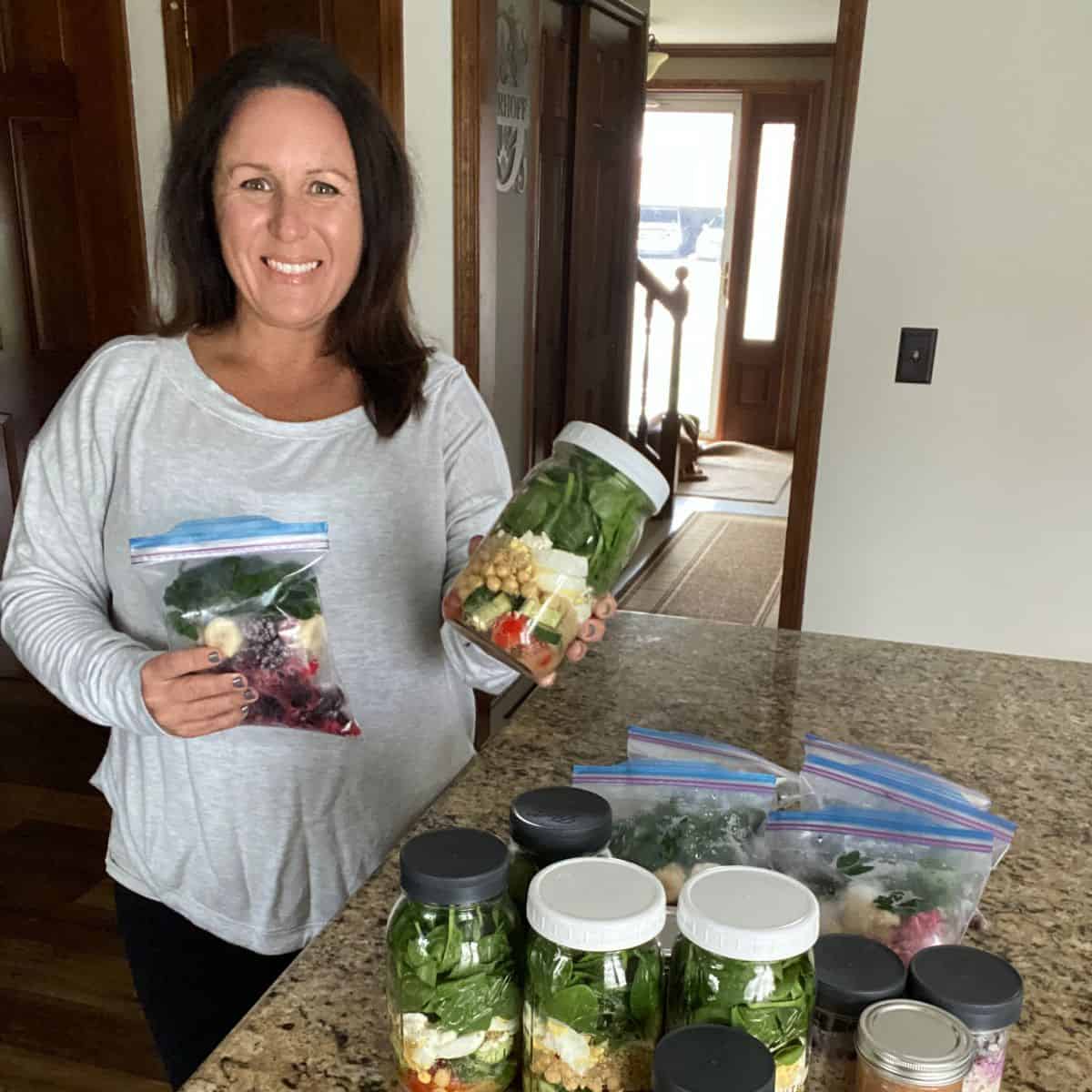 me holding a mason jar salad and smoothie kit for meal prep.