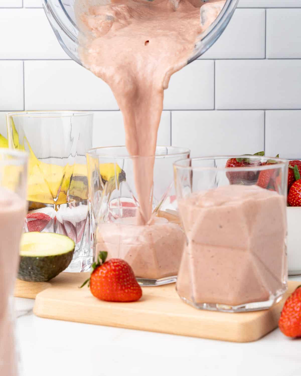 strawberry avocado smoothie being poured into a glass.