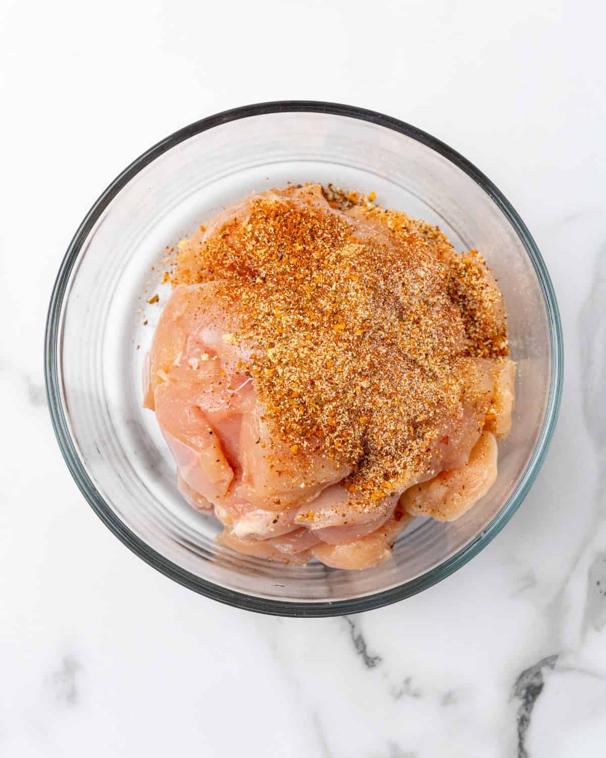 cajun seasoning in a bowl with chicken pieces.