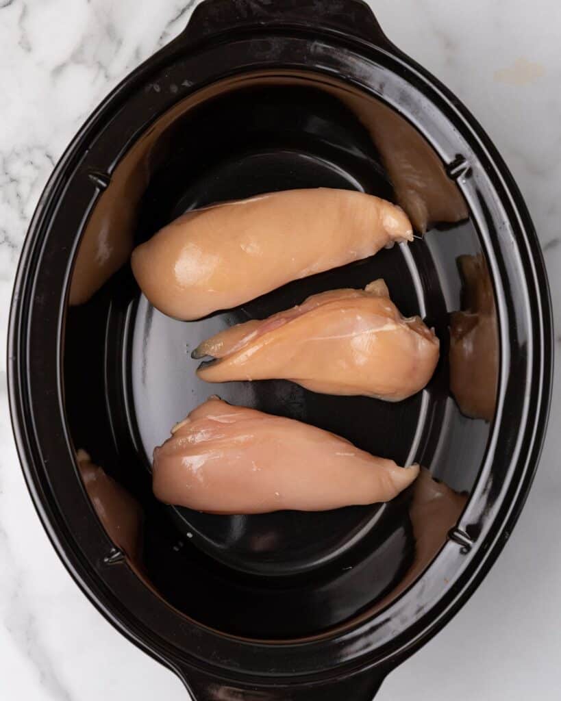 raw chicken breasts in a slow cooker.