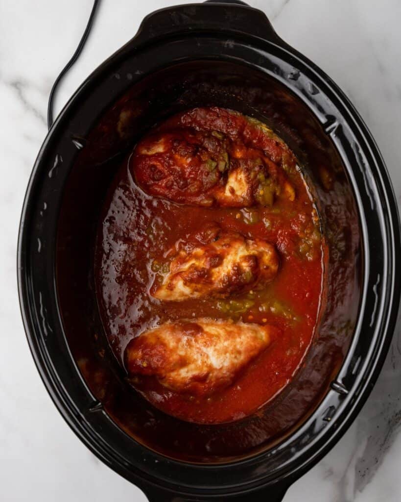 chicken cooked in the sauce in the slowcooker.