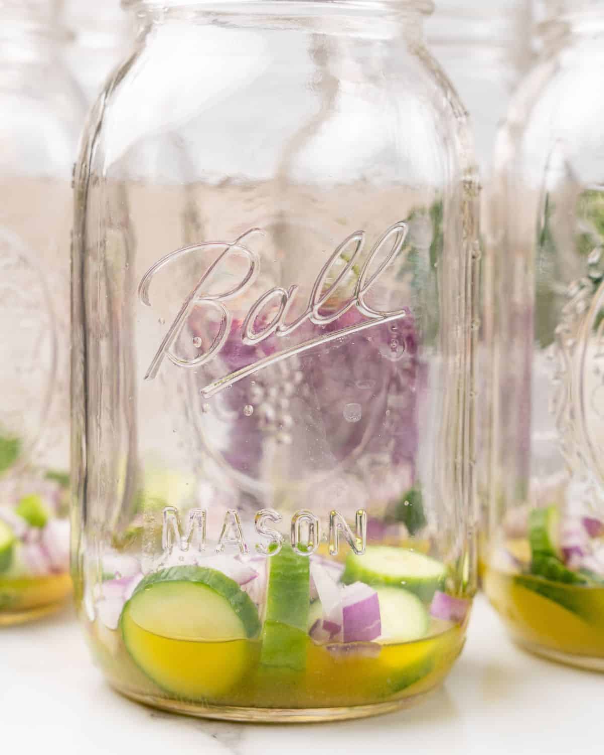 dressing with cucumbers and onion layered in mason jar.
