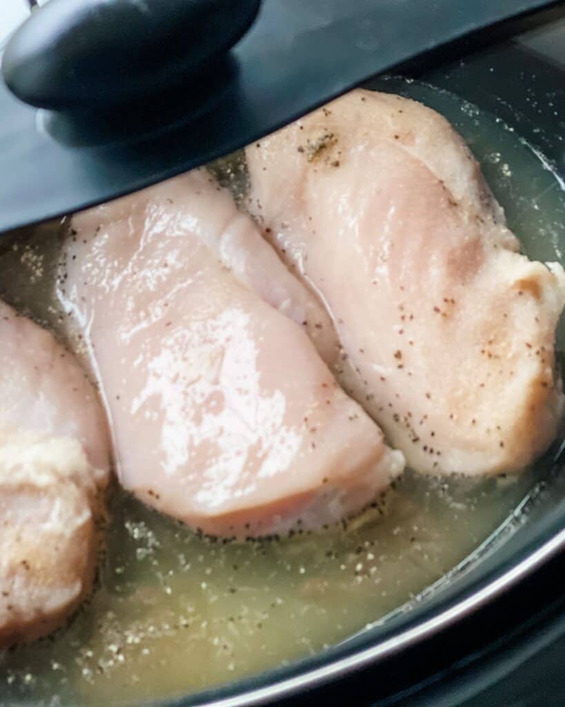 lid on the slow cooker with the raw chicken breasts and broth in.