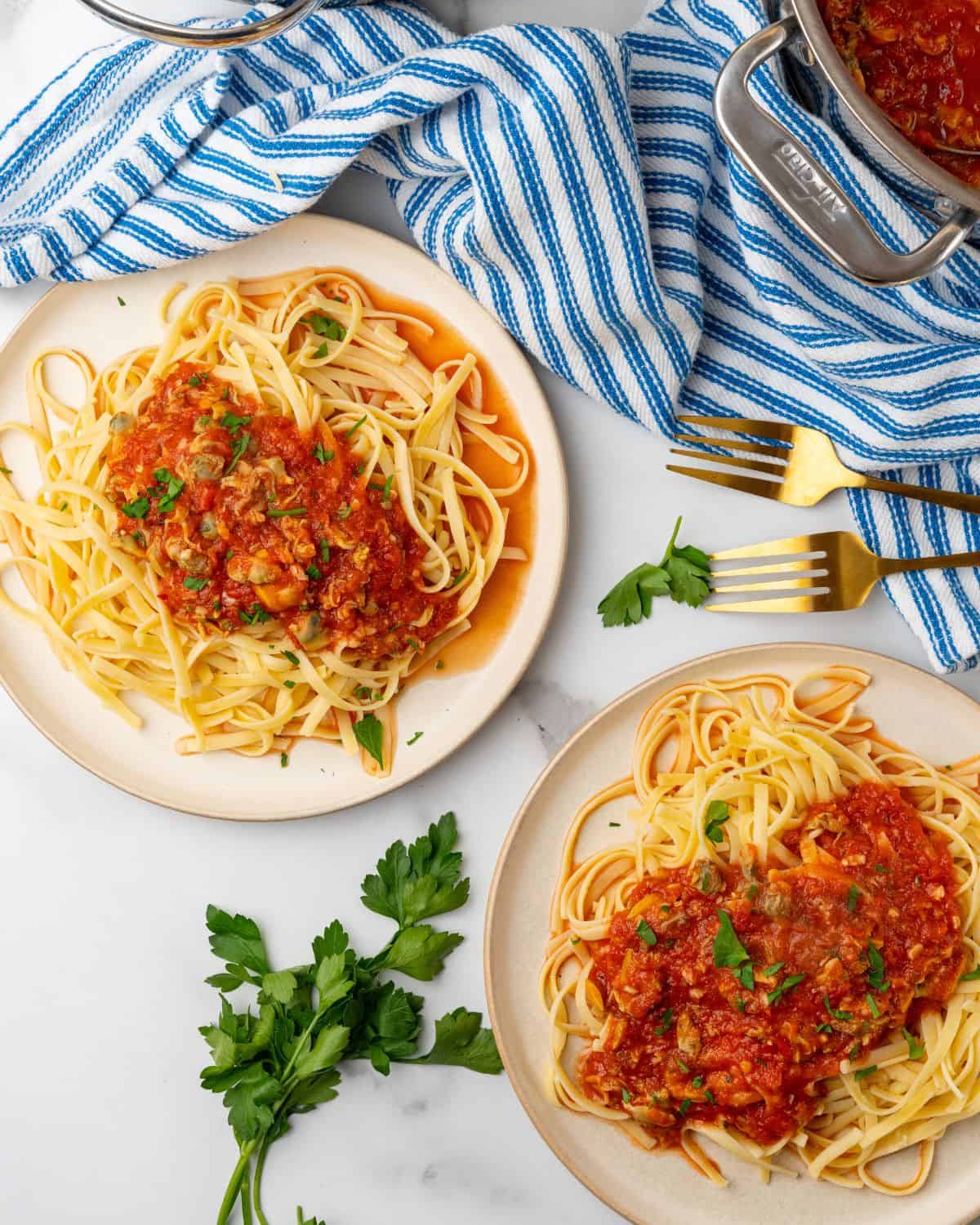 overhead picture of two plates of linguine and red clam sauce.