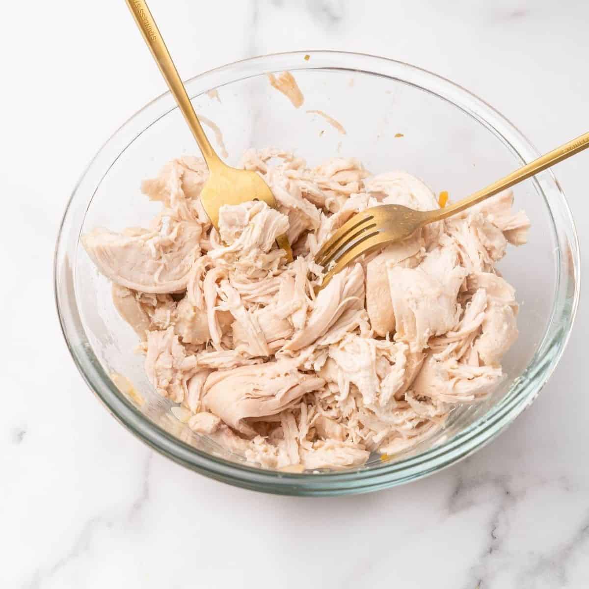 healthy crockpot shredded chicken in a glass bowll.