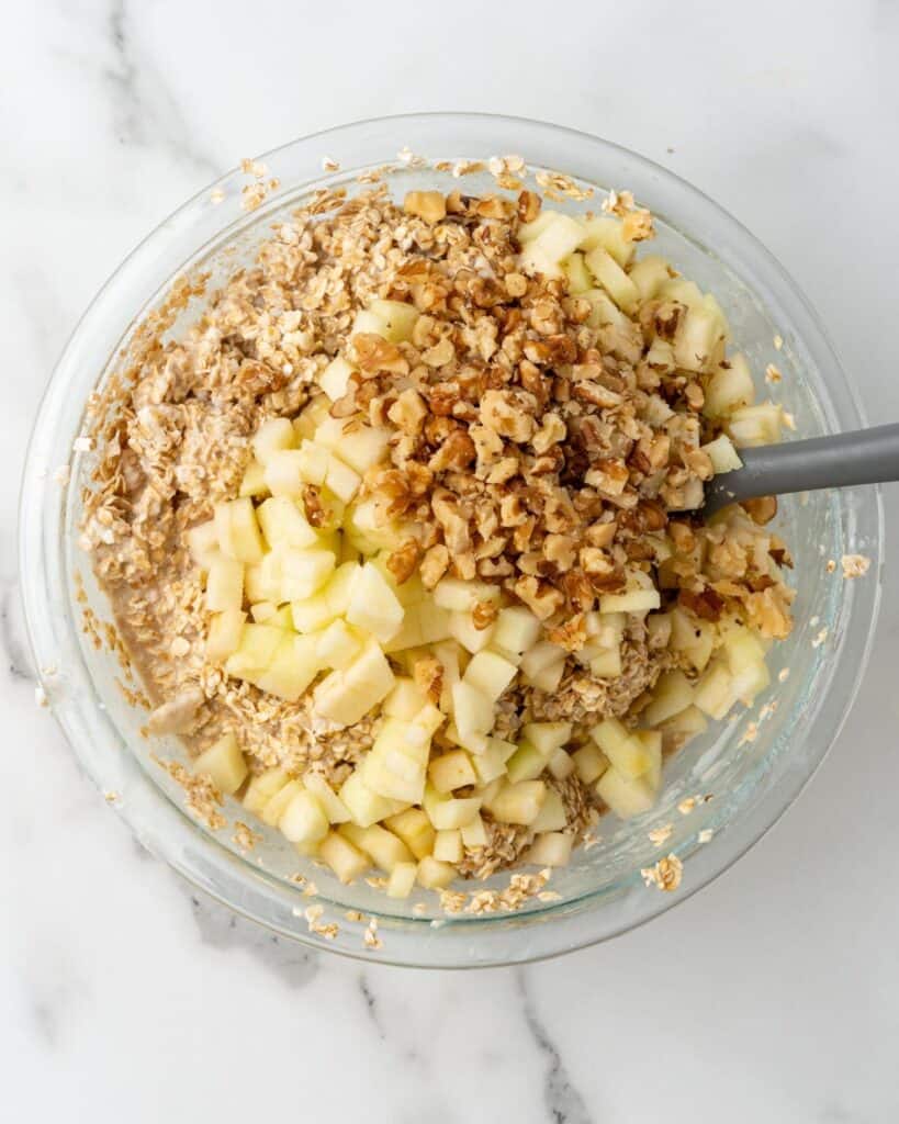 apples and walnuts mixed in bowl with oatmeal batter.