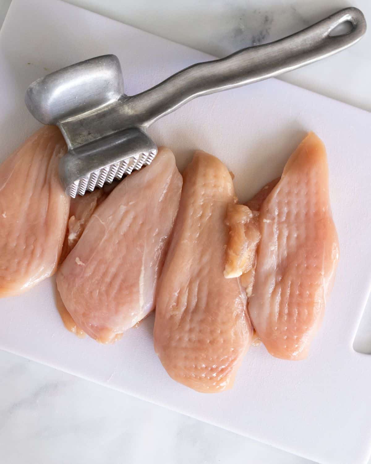 pounded out chicken on a cutting board.